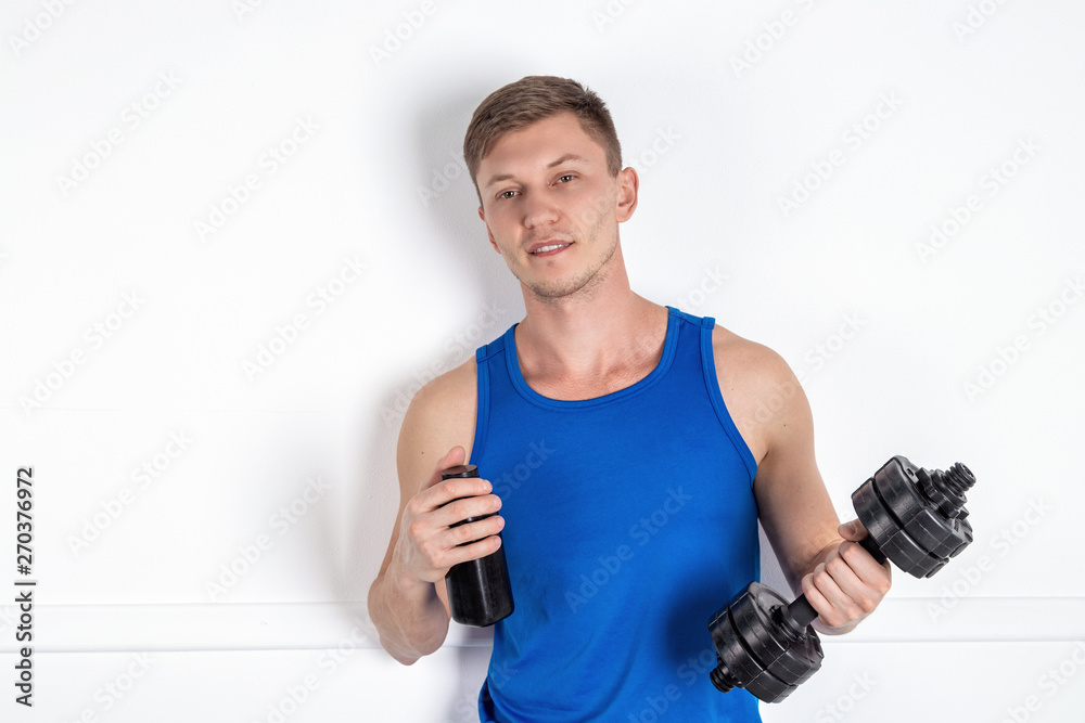 Handsome young man in blue shirt lifting dumbbell. White background Handsome young man in blue shirt lifting dumbbell. White background
