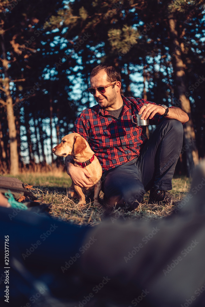 Hiker with friends and his dog resting and drinking coffee