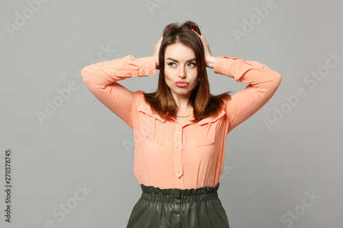 Portrait of pensive young woman in pastel casual clothes looking aside putting hands on head isolated on gray wall background in studio. People sincere emotions, lifestyle concept. Mock up copy space.