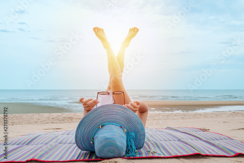 Fototapeta Naklejka Na Ścianę i Meble -  portrait of female with hat relaxing on beach mat by beach