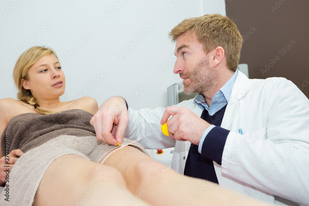 Fototapeta premium aesthetic doctor measuring womans leg