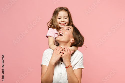 Woman in light clothes have fun with cute child baby girl. Mother, little kid daughter isolated on pastel pink wall background, studio portrait. Mother's Day, love family, parenthood childhood concept photo