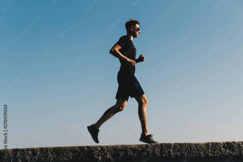 Young running man on sky background at sunrise Young running man on sky background at sunrise