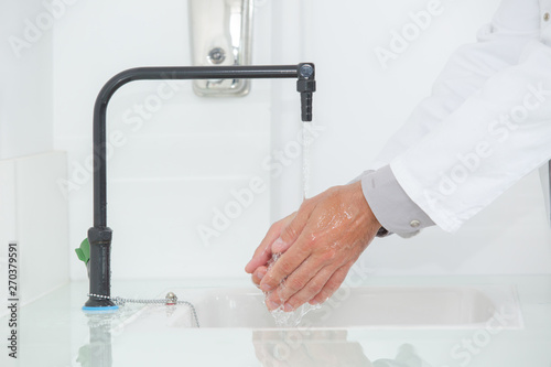 Fotografija Person wearing labcoat washing their hands