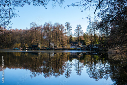 Ein See in Brandenburg, Bootsanleger und Waldrand am gegenüberliegenden Ufer spiegeln sich auf der Wasseroberfläche