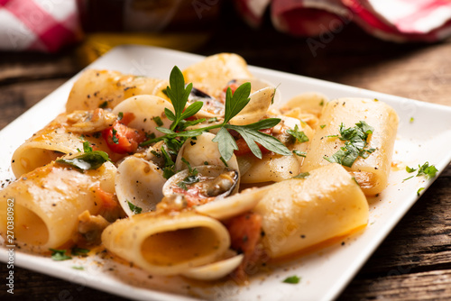 Paccheri pasta with clams on white plate