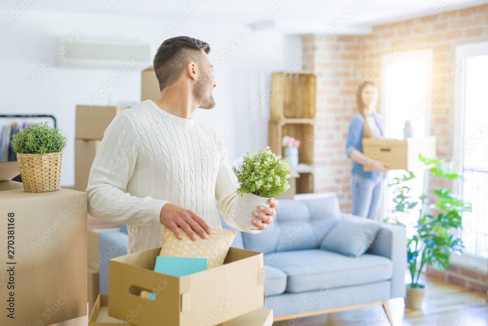 Young couple moving to a new home, handsome man smiling moving cardboard box Young couple moving to a new home, handsome man smiling moving cardboard box
