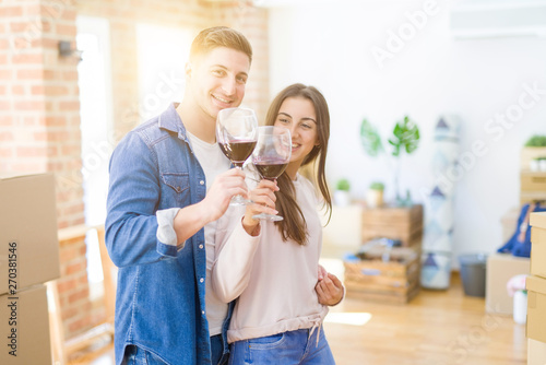 Young beautiful couple drinking a glass of wine celebrating moving to a new house