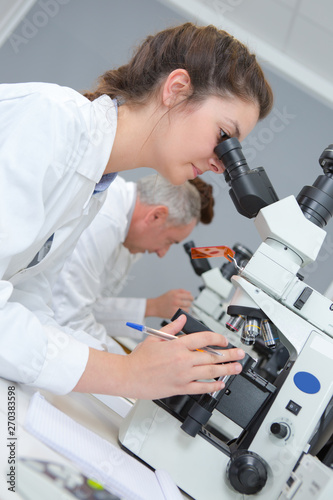 female scientist looking through a microscope in laboratory