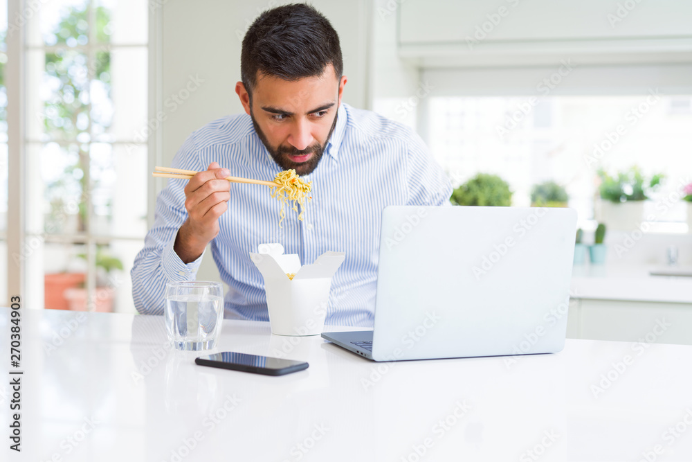 Business man eating asian food from delivery while working using computer laptop at the office