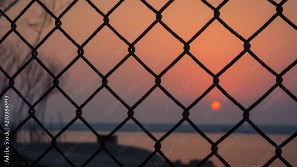 Naklejka premium Sunset captured through the fence