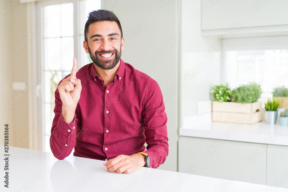 Handsome hispanic business man showing and pointing up with finger number one while smiling confident and happy.