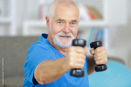 elderly man exercising with dummbells at home