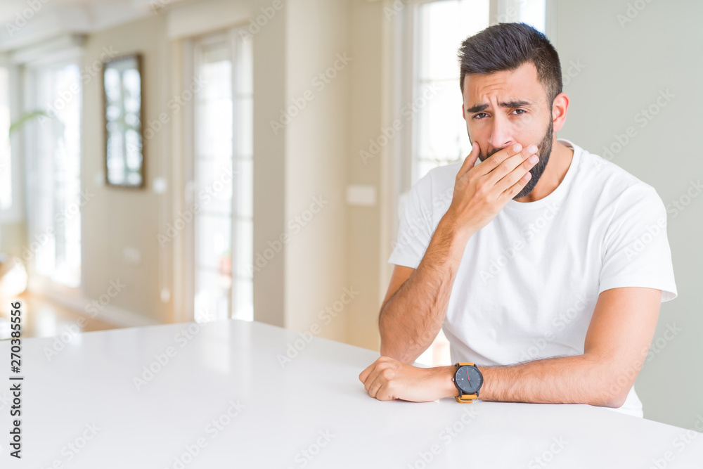 Handsome hispanic man casual white t-shirt at home bored yawning tired covering mouth with hand. Restless and sleepiness.