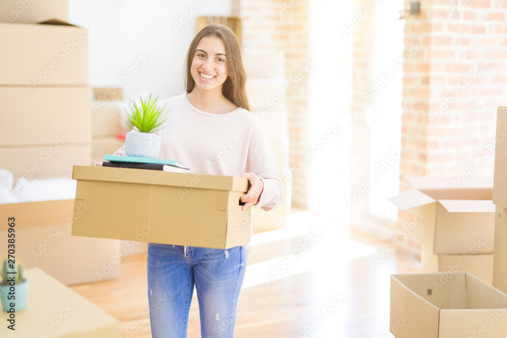 Beautiful young woman smiling happy moving to a new home, very excited holding cardboard boxes at new apartment Beautiful young woman smiling happy moving to a new home, very excited holding cardboard boxes at new apartment