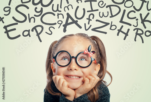 beautiful cute little girl looking at with handwritten letters of alphabet above her head