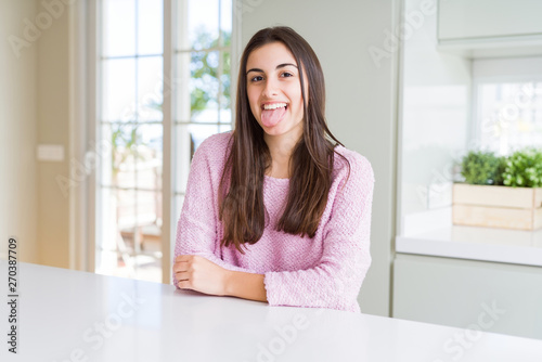 Free Download Beautiful young woman wearing pink sweater sticking tongue out happy with funny expression. Emotion concept. - GFXLoad