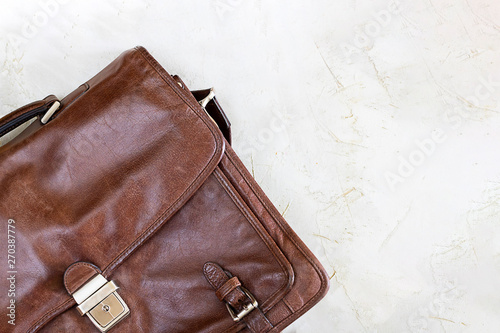 brown leather bag for business man with mockup metal decorative fastener on grey textured cement surface, conctere wall for background. Horizontal copy space for text and design. Accessory. Top view photo