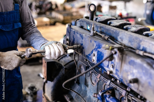 Mechanic repairs old motor of truck in a car repair station. Disassemble engine block vehicle. Motor capital repair. Car service concept