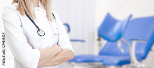 Gynecological banner with copyspace for text. Gynecologist doctor in white uniform in clinic hospital. cabinet with blue chair on background. Woman health and pregnancy concept. photo