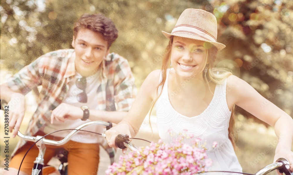 Happy young couple cycling through the park