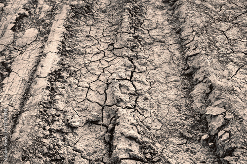 Car tire tracks on the cracked ground. Texture of cracks in the dry earth.