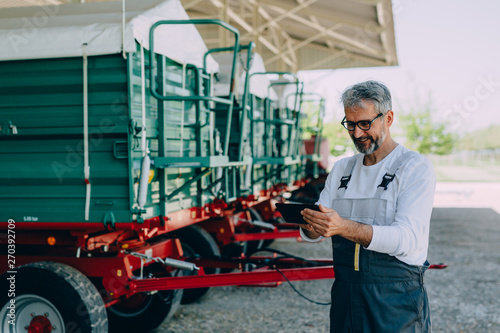 worker using tablet standing in front of agricultural machinery