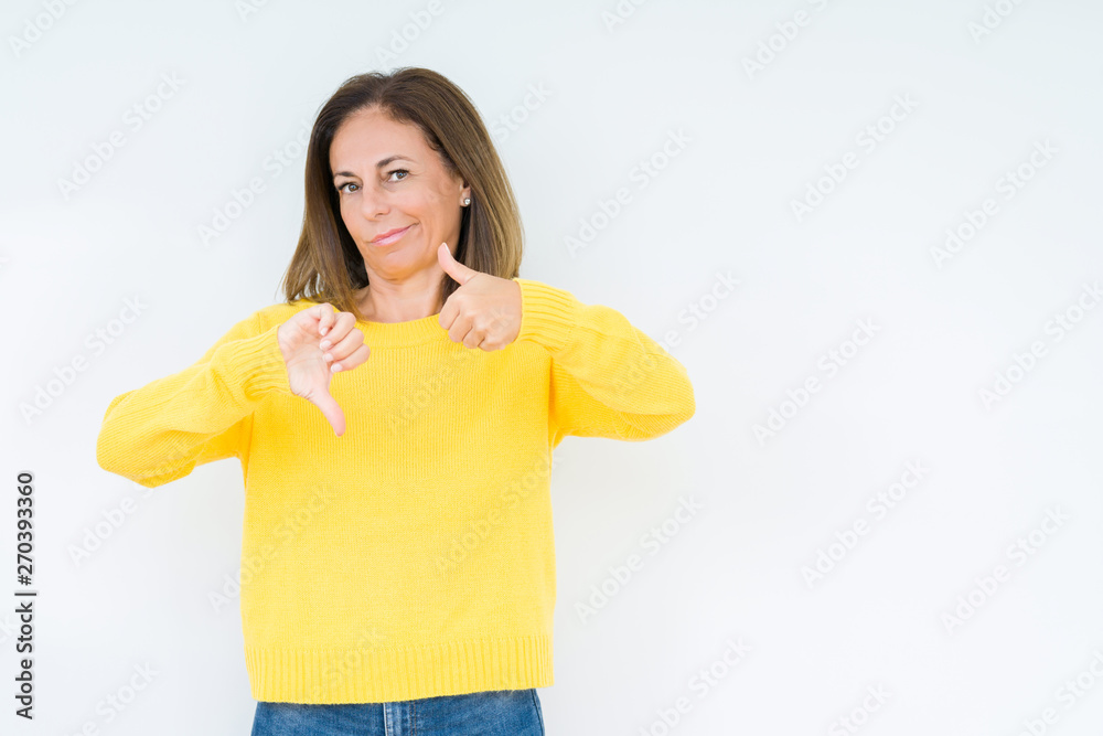 Beautiful middle age woman wearing yellow sweater over isolated background Doing thumbs up and down, disagreement and agreement expression. Crazy conflict Beautiful middle age woman wearing yellow sweater over isolated background Doing thumbs up and down, disagreement and agreement expression. Crazy conflict