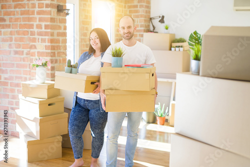 Young couple moving to a new home, smiling happy holding cardboard boxes © Krakenimages.com