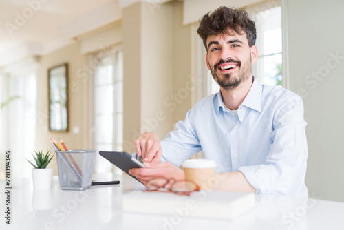 Young business man using touchpad tablet very happy pointing with hand and finger