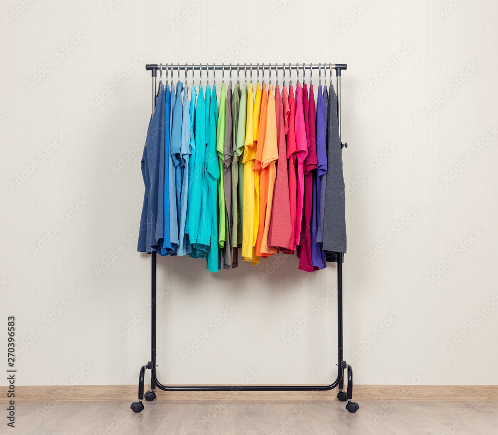 Mobile rack, with colorful T-shirts on the background of the wall
