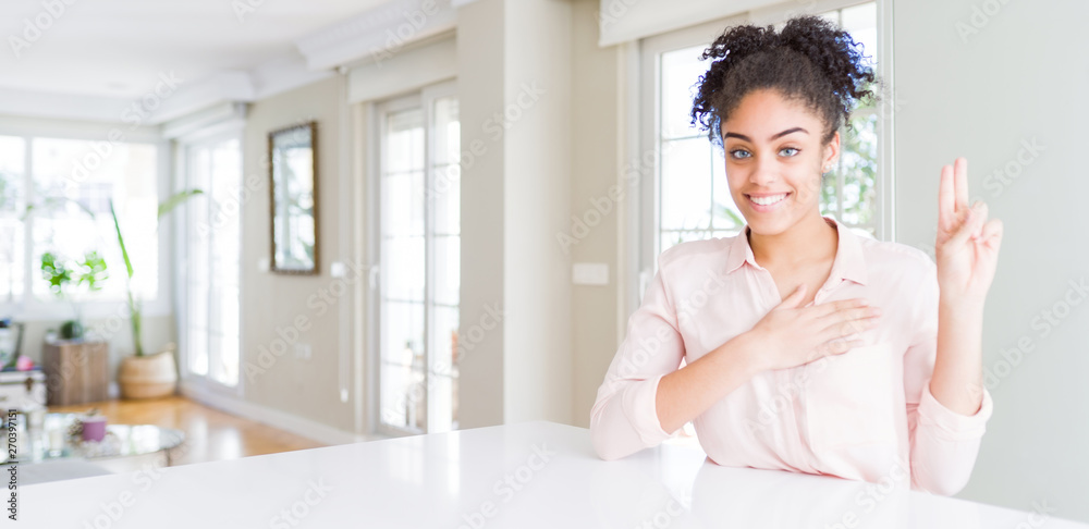 Wide angle of beautiful african american woman with afro hair smiling swearing with hand on chest and fingers up, making a loyalty promise oath Wide angle of beautiful african american woman with afro hair smiling swearing with hand on chest and fingers up, making a loyalty promise oath