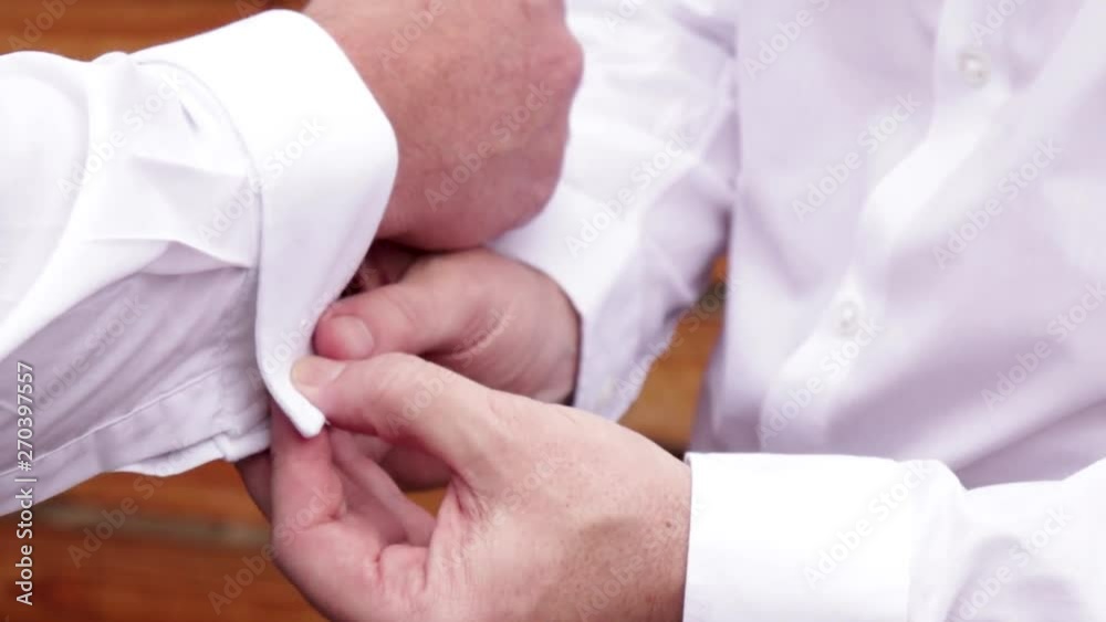 Close-up of cuff links being inserted into cuffs. Close-up of cuff links being inserted into cuffs.