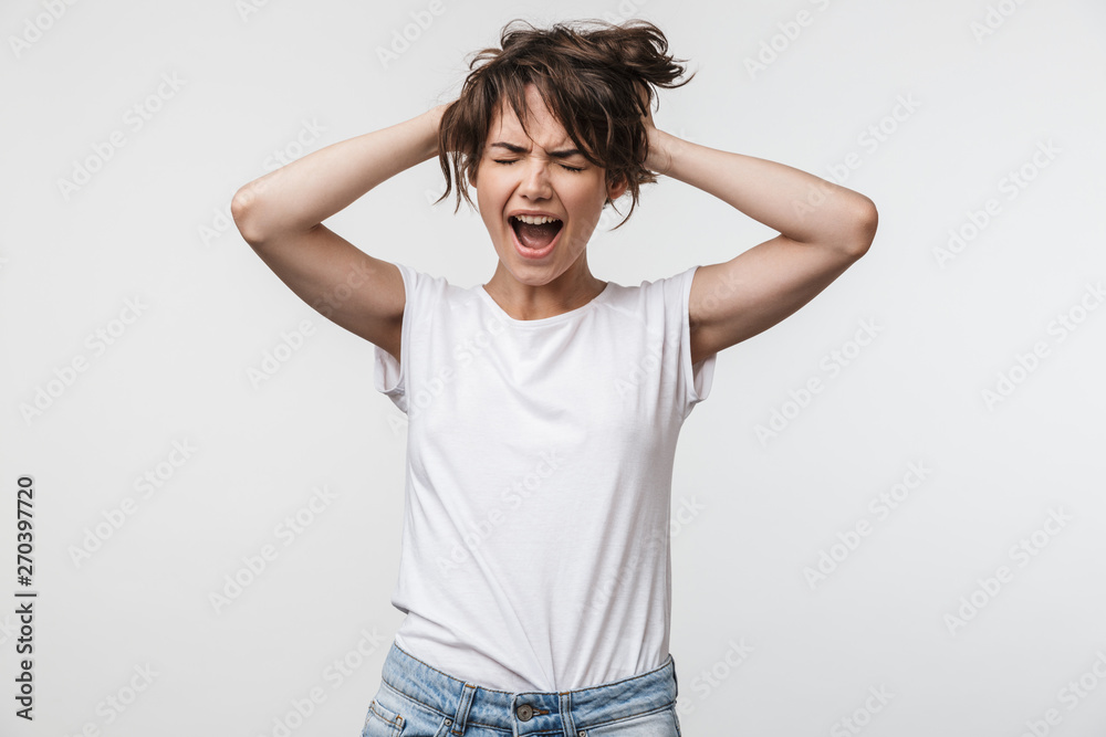 Image of shocked woman with short hair in basic t-shirt screaming and grabbing her head
