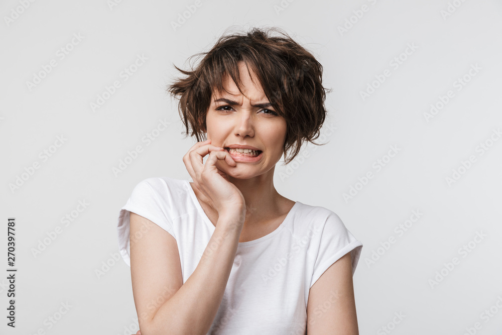 Portrait of upset woman with short brown hair in basic t-shirt frowning and looking at camera Portrait of upset woman with short brown hair in basic t-shirt frowning and looking at camera