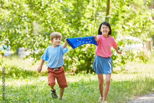 Kinder laufen mit Europa Fahne im Park