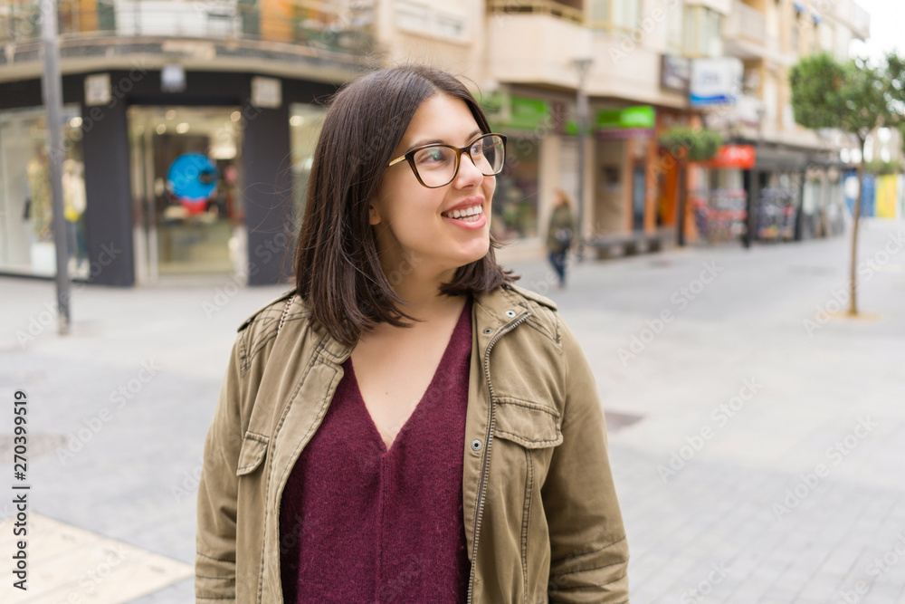 Beautiful young woman wearing glasses smiling confident at the streets of the town