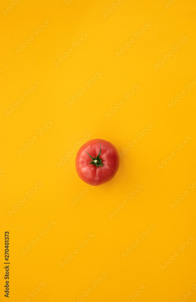 Fototapeta Close up ripe tomato on bright yellow background top view flat lay. Summer abstract background with tomato