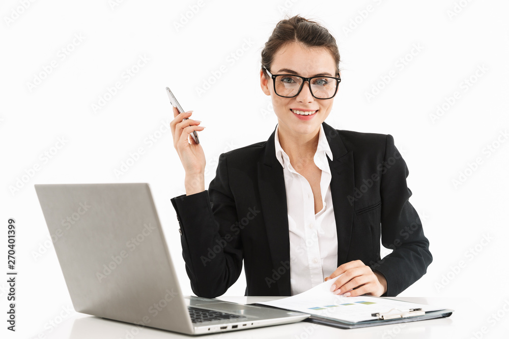 Photo of happy female worker businesswoman dressed in formal wear sitting at desk and working on laptop in office Photo of happy female worker businesswoman dressed in formal wear sitting at desk and working on laptop in office