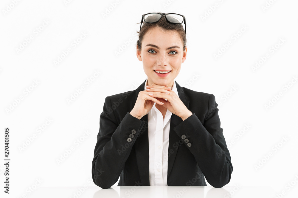 Photo of charming female worker businesswoman dressed in formal wear looking at camera while working and sitting at desk in office Photo of charming female worker businesswoman dressed in formal wear looking at camera while working and sitting at desk in office