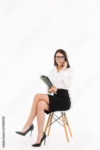 Photo of pretty female worker businesswoman dressed in formal wear talking on smartphone while sitting in office chair