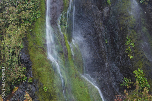 緑の岩肌を流れる滝