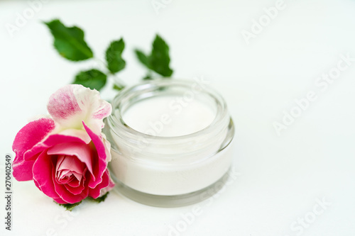 Face and body cream with pink rose isolated on white background with copy space