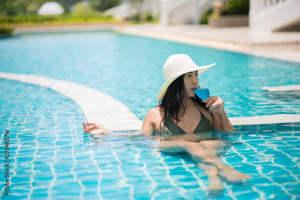 Young Woman Wearing Hat Drinking Juice While Relaxing In Swimming Pool