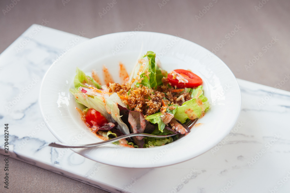 Fresh green mix salad with crispy crumb in white bowl