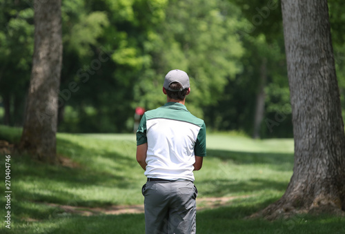 Photography A junior golfer prepares to hit a shot between two trees