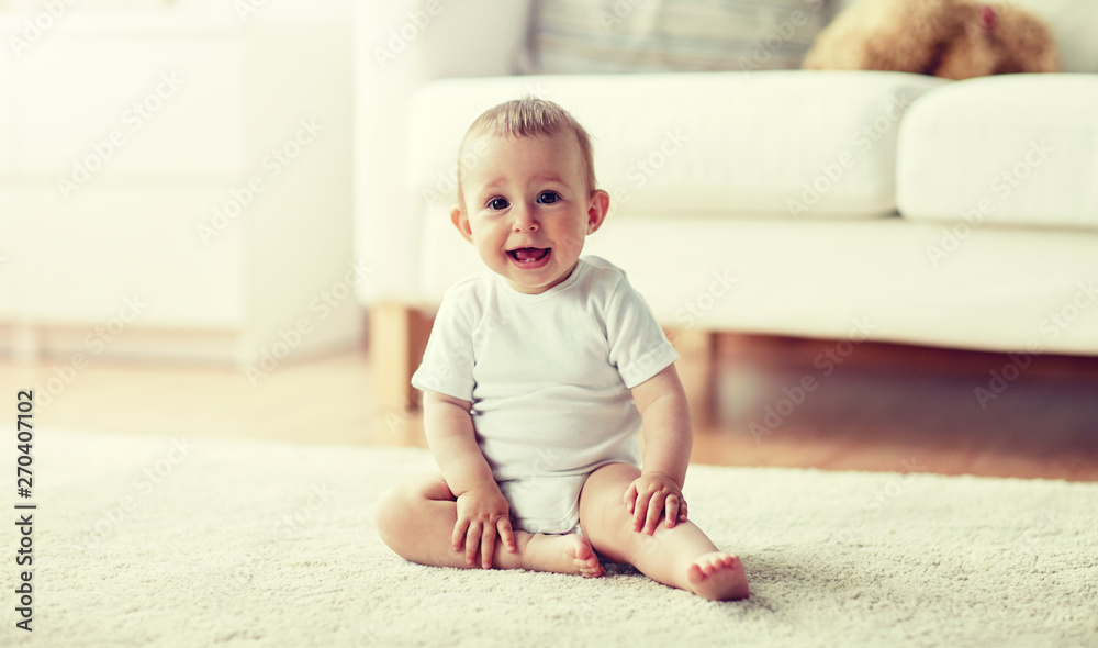 childhood, babyhood and people concept - happy little baby boy or girl sitting on floor at home childhood, babyhood and people concept - happy little baby boy or girl sitting on floor at home
