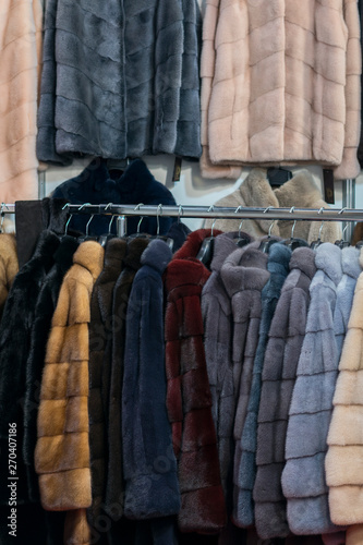 Luxury mink coats. Pink, grey, dark grey, pearl color fur coats on showcase of market. Best gift for a woman. Outerwear. Close up. vertical photo