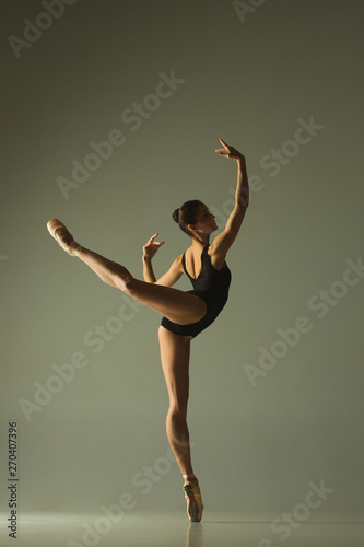 Graceful ballet dancer or classic ballerina dancing isolated on grey studio background. Showing flexibility and grace. The dance, artist, contemporary, movement, action and motion concept.