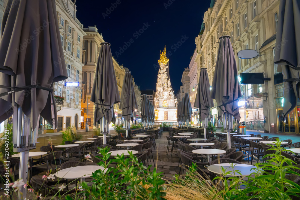 Naklejka premium Nightscape of Graben street with street cafe and Plague Column, Austria, Vienna